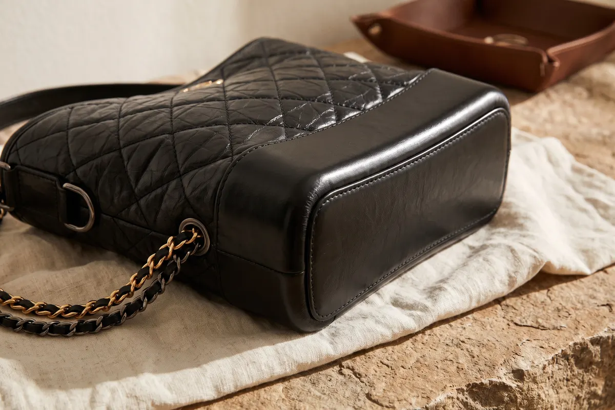 Bord de la base et chaîne aux métaux mixtes d’un sac Gabrielle Chanel en veau noir