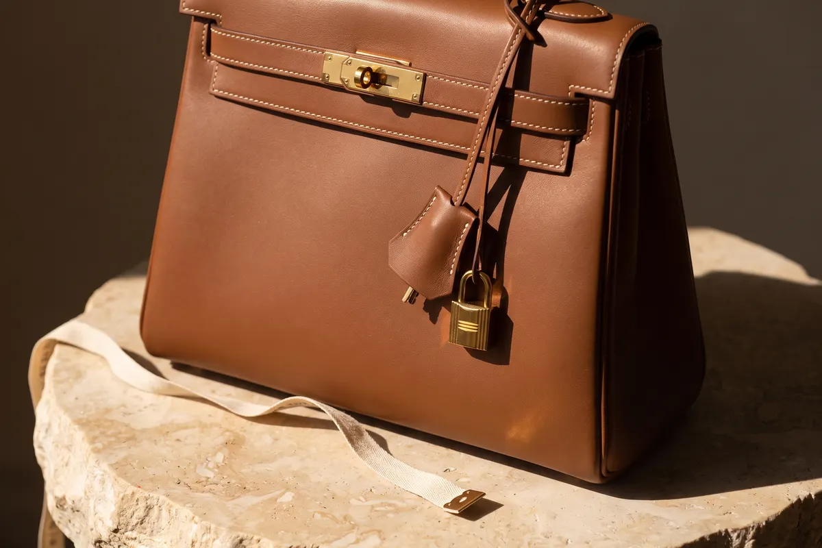 Kelly flap, turn-lock and stitching with a tape measure, comparing Hermès Kelly sizes