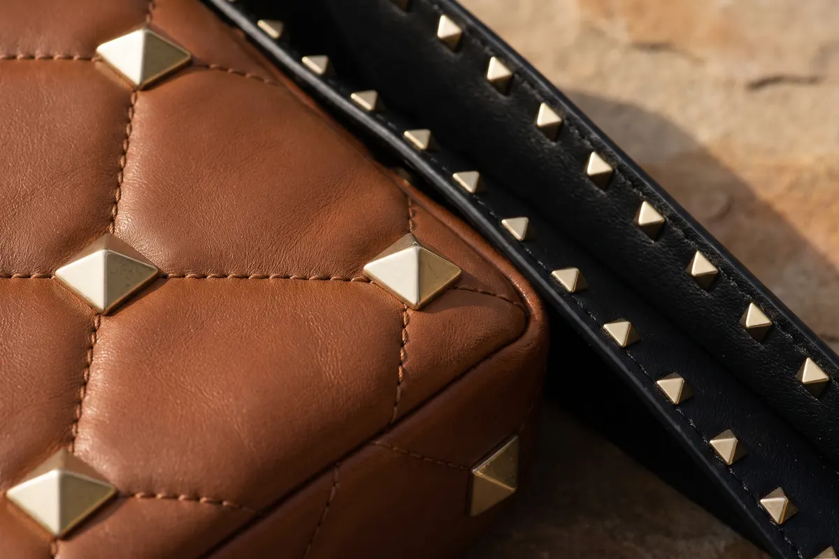 Gros plan sur les clous pyramidaux d’un sac Valentino Rockstud à côté du cuir matelassé d’un Spike